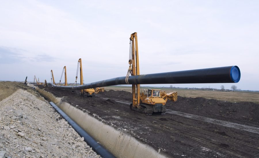 Heavy duty construction machines carrying and placing gas pipe into the ground.